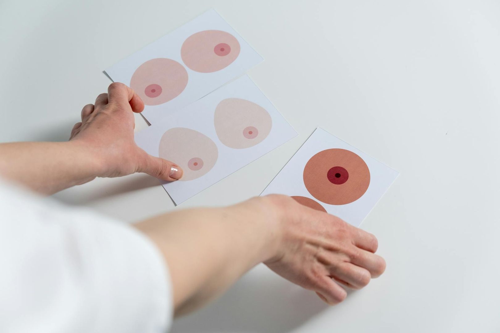 Händer håller upp kort med illustrationer av bröstvårtor i olika nyanser.